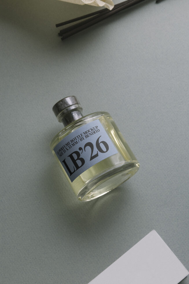 Amber glass perfume bottle with label mockup on pale neutral surface