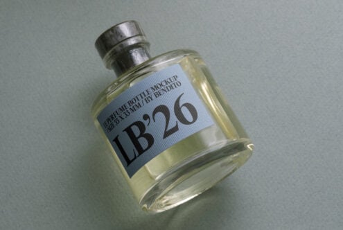 Clear fragrance bottle with blue label on light neutral background