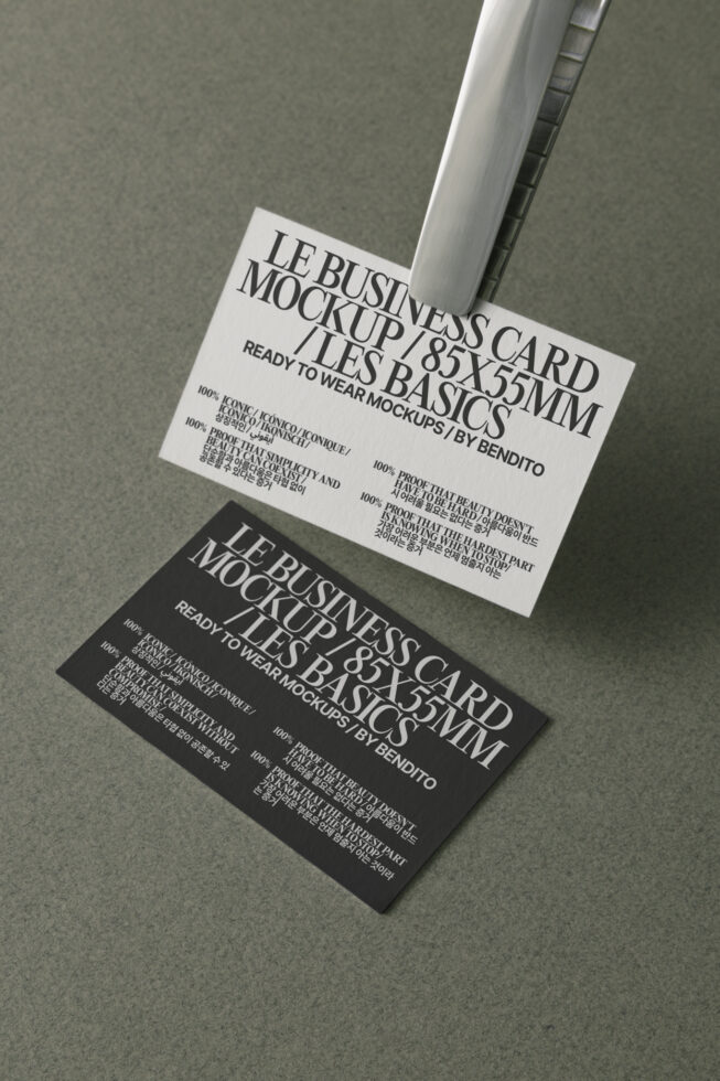 White black business cards overlapped, angled overhead, metallic clip holder shadow