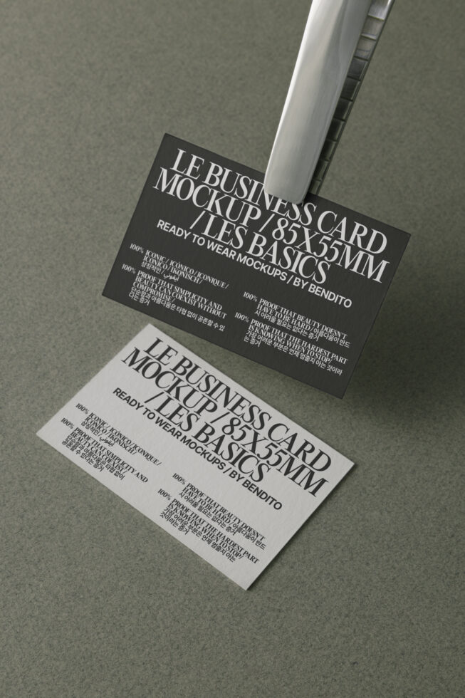 Black white business cards stacked, angled overhead, metallic clip holder shadow