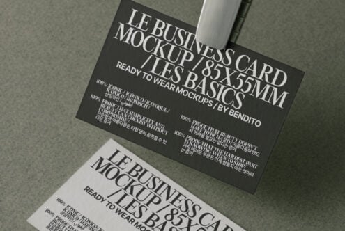 Black business card with white serif typography, shot overhead at angle on neutral background