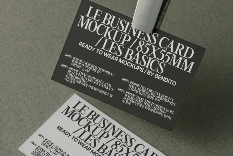 Black business card with white serif typography, shot overhead at angle on neutral background