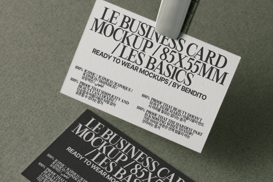 White business card with black serif typography, shot overhead at angle on neutral background