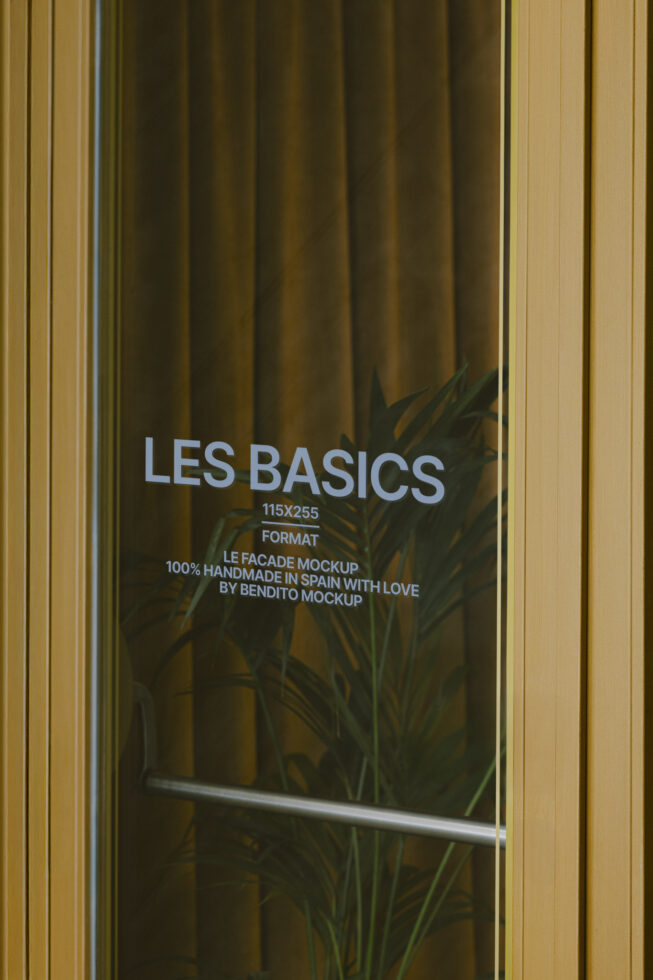 Storefront window with Les Basics text, plant shadow, gold frame on olive curtain backdrop
