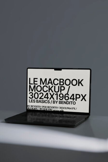 MacBook mockup with cream screen displaying black typography in side angle view