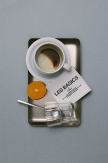 Overhead shot of espresso, citrus slice, business card, glass spoon on tray