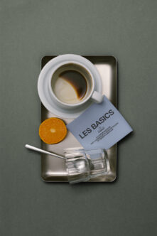 Flat lay overhead of coffee cup, orange slice, business card, glass with straw