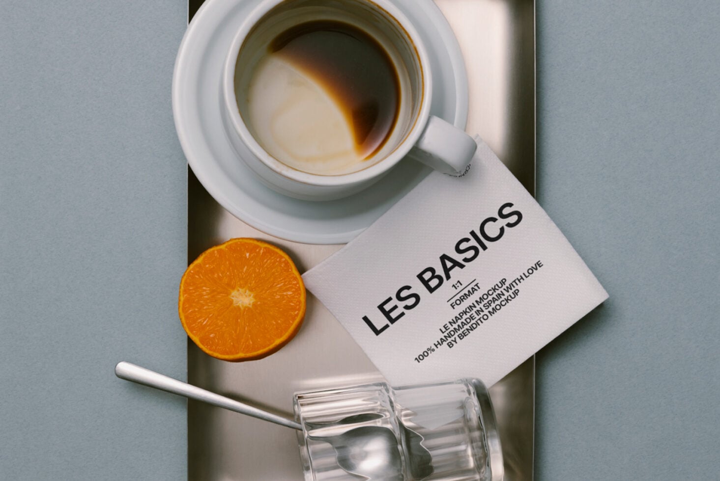 Styled flat lay of coffee mug, orange wedge, business card, clear glass