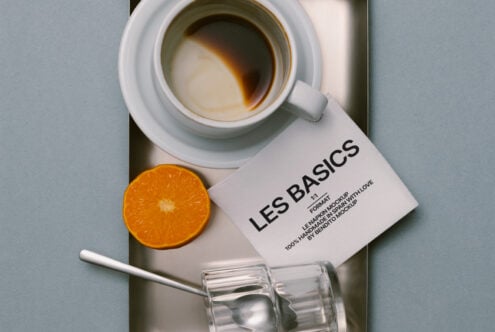Styled flat lay of coffee mug, orange wedge, business card, clear glass