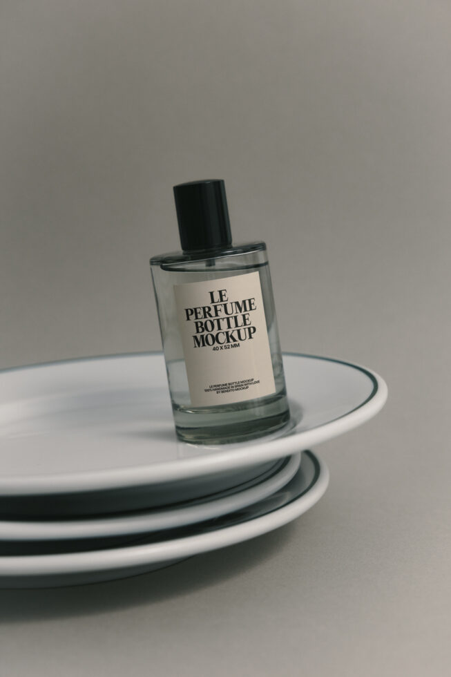 Clear perfume bottle mockup with cream label on circular plate stack