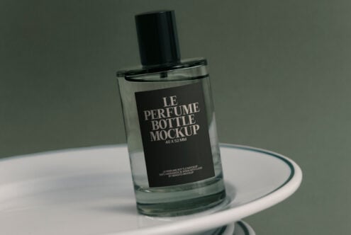 Fragrance bottle with black label displayed on white ceramic dishes
