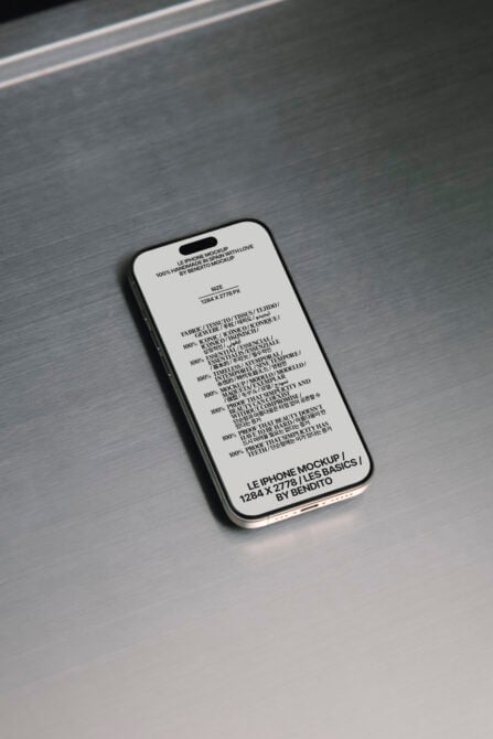 iPhone mockup with cream screen showing multilingual text on brushed metal surface
