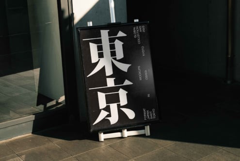 Bold vertical kanji sign mockup in black, angled outdoor storefront display