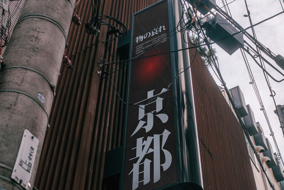 Vertical banner with Japanese characters mounted on dark building facade with tangled power lines