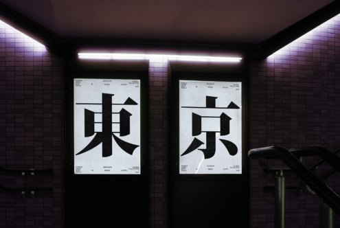Two posters under purple neon in tiled subway with black Japanese typography