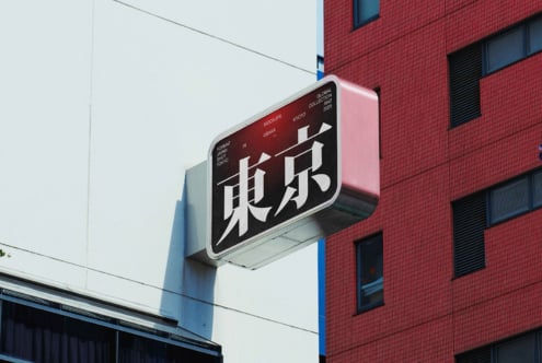 Red street sign with Japanese characters mounted on brick building wall