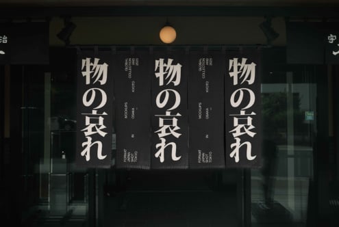 Dark fabric banners with white kanji text mounted above glass storefront