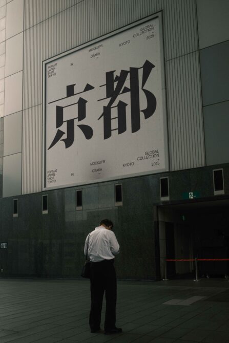 Man standing beneath massive outdoor billboard featuring striking Japanese character design