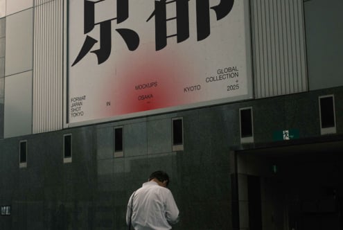 Building billboard showing Japanese kanji with red gradient, figure viewing from street level