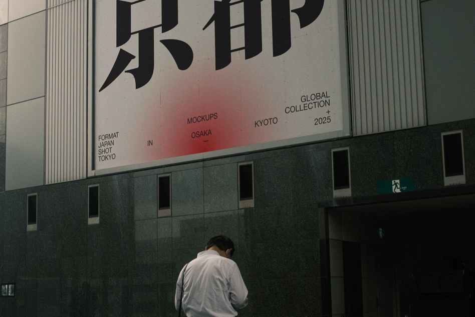 Building billboard showing Japanese kanji with red gradient, figure viewing from street level