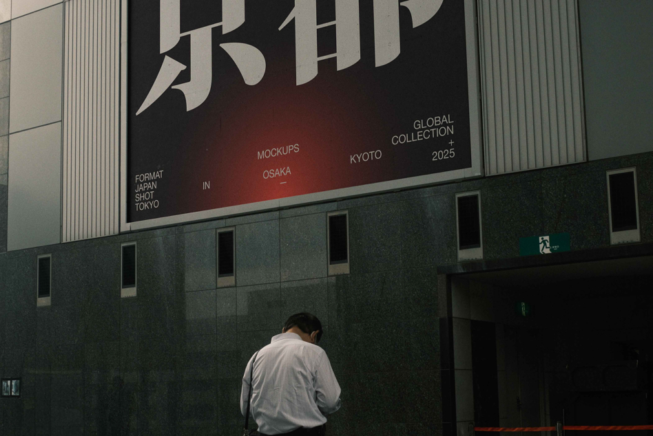 Large building banner with bold Japanese characters, person standing below against green facade