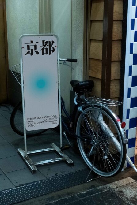 Standee sign with Japanese characters next to parked bicycle indoors