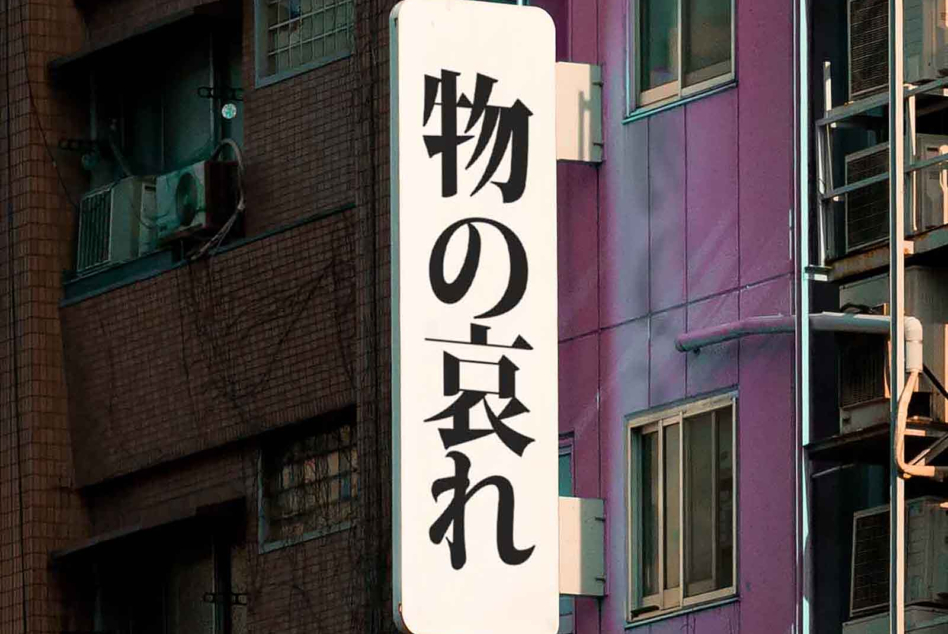 Vertical white sign with black Japanese characters on colorful building