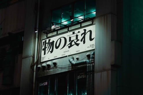 Nighttime shot of illuminated street sign with Japanese characters in Osaka