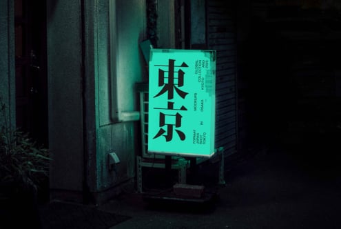 Glowing mint green box sign with black kanji text mounted on brick wall