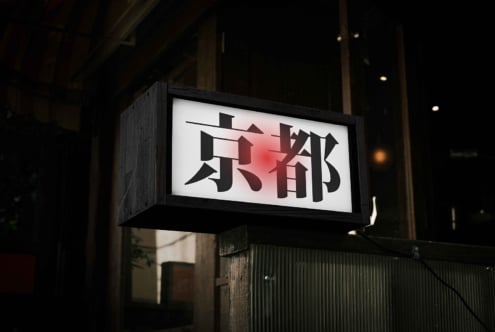 Nighttime illuminated sign with black kanji on white light and red gradient accent