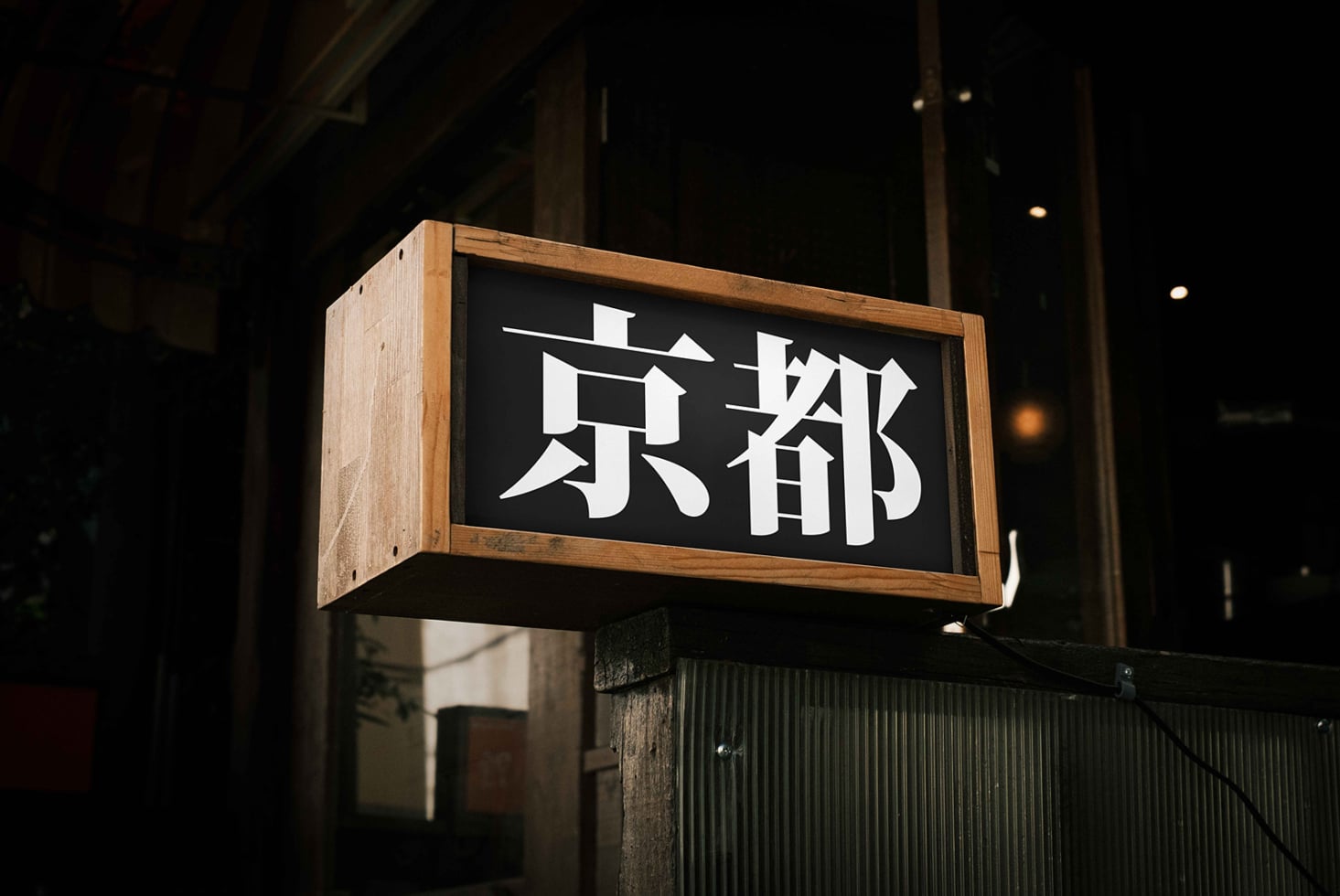 Wooden framed nighttime street sign with white kanji characters on black background