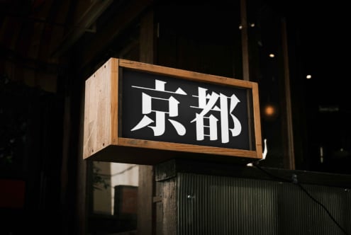 Wooden framed nighttime street sign with white kanji characters on black background