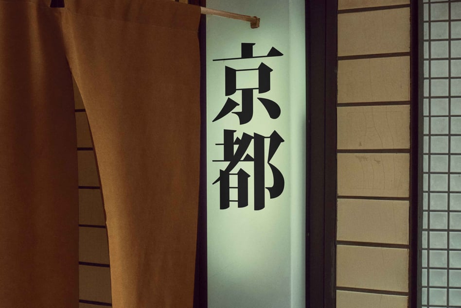Lit kanji characters in pale green glow on dark panel with traditional wooden framing