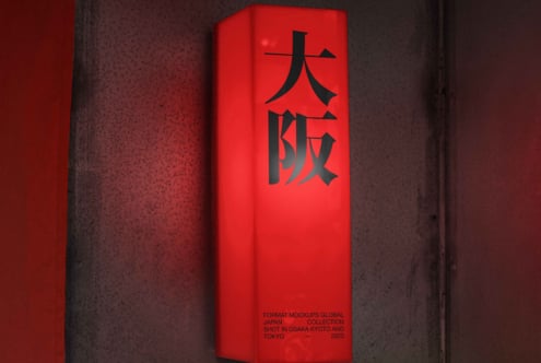 Bright red tall box with black kanji characters on textured concrete backdrop