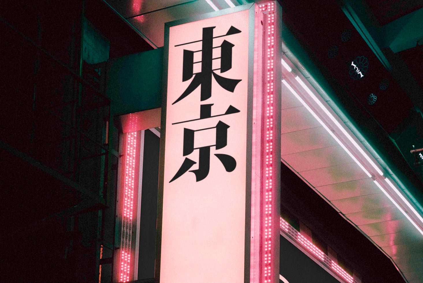Neon-lit signage with pink illumination displaying black Japanese characters vertically