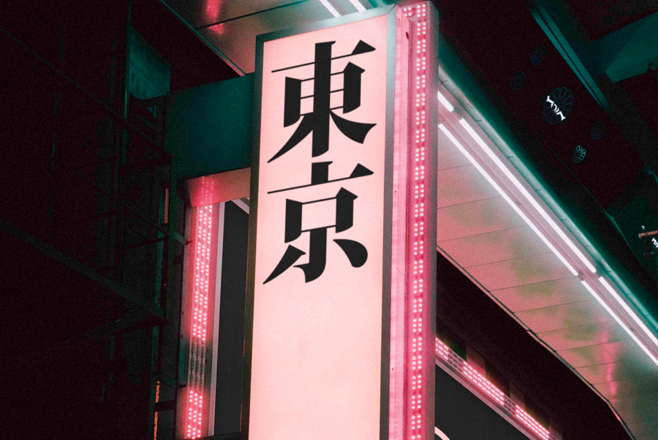 Neon-lit signage with pink illumination displaying black Japanese characters vertically