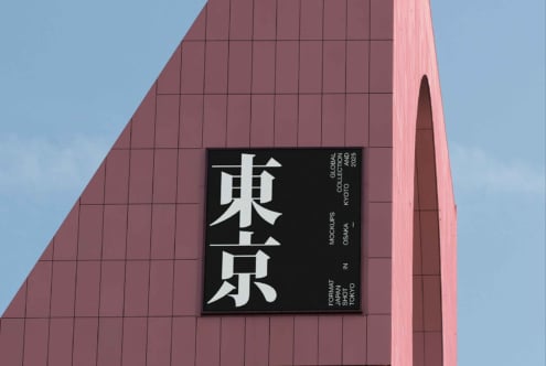 Black sign displaying white Japanese kanji on mauve colored architectural structure