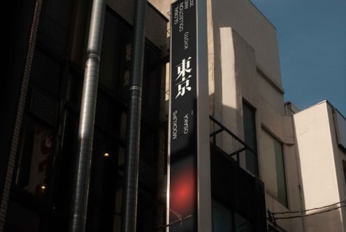 Dark vertical signage with white text showing Japanese characters lit at night