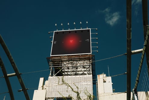 Vintage rooftop billboard with red glowing center against deep blue sky