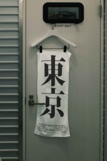 White tank top on hanger with bold black kanji, staff room sign above it