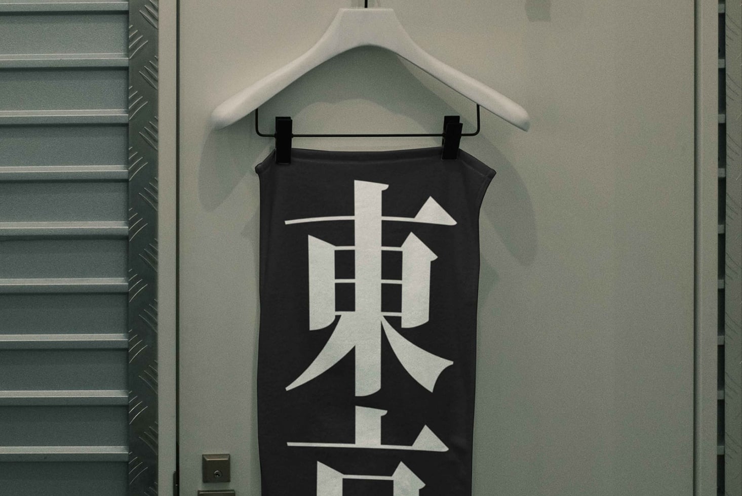 Black tank top with white geometric kanji character design hanging on white hanger