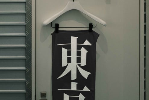 Black tank top with white geometric kanji character design hanging on white hanger