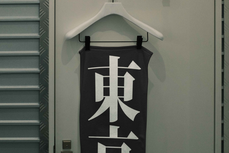 Black tank top with white geometric kanji character design hanging on white hanger