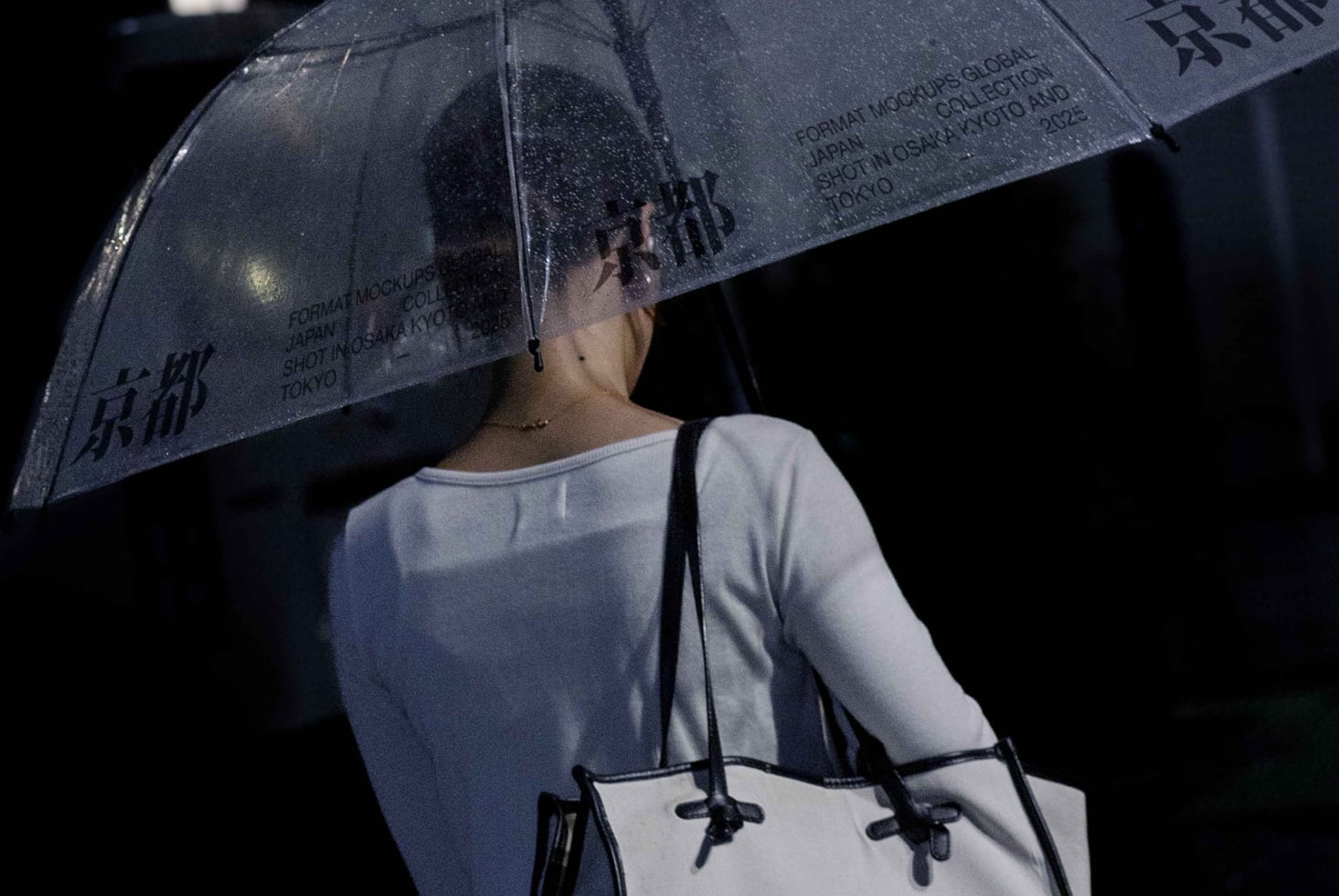Person holding dark umbrella with printed text overhead shot minimal lighting