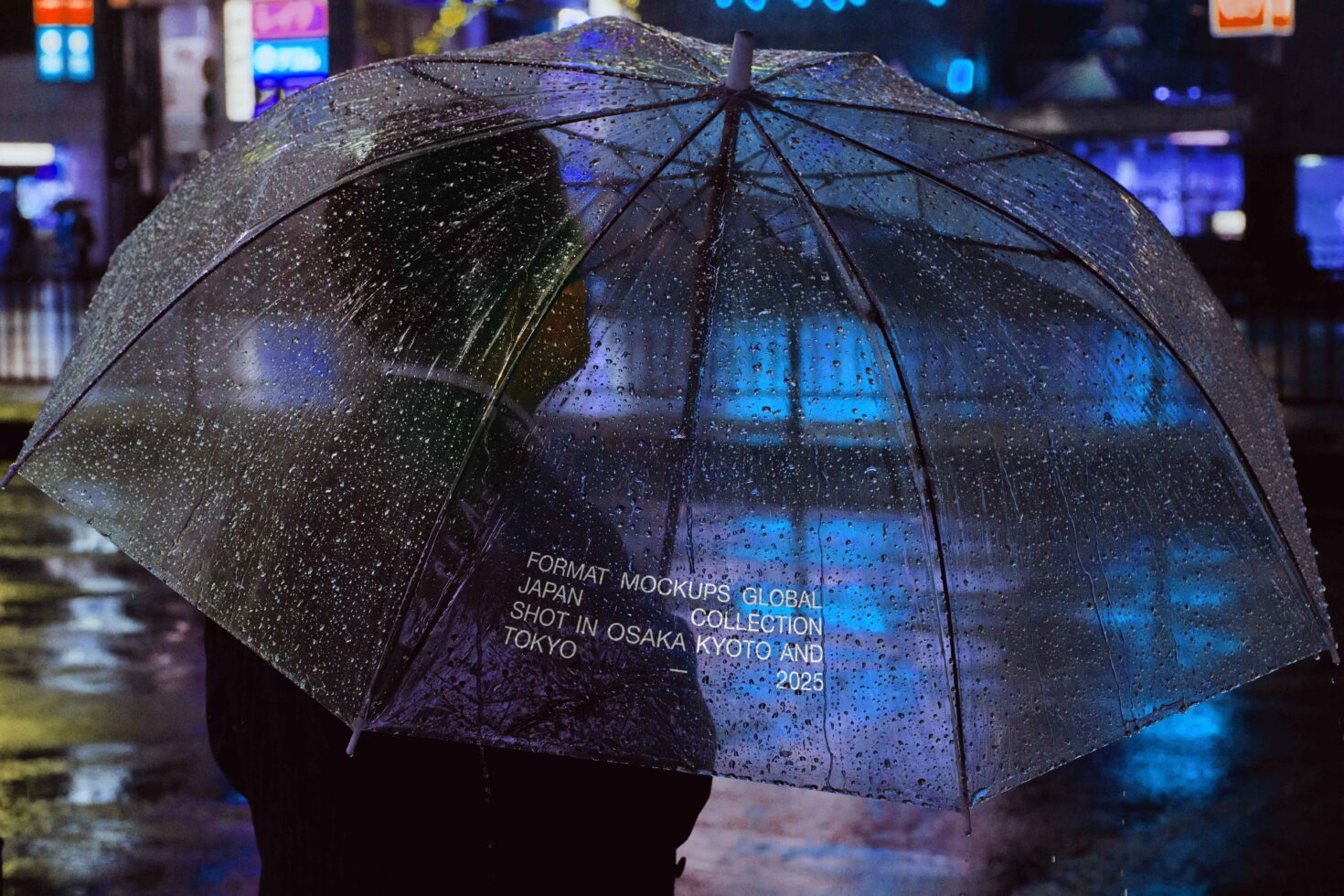 Clear umbrella with Japanese text printed on wet surface reflecting blue neon city lights