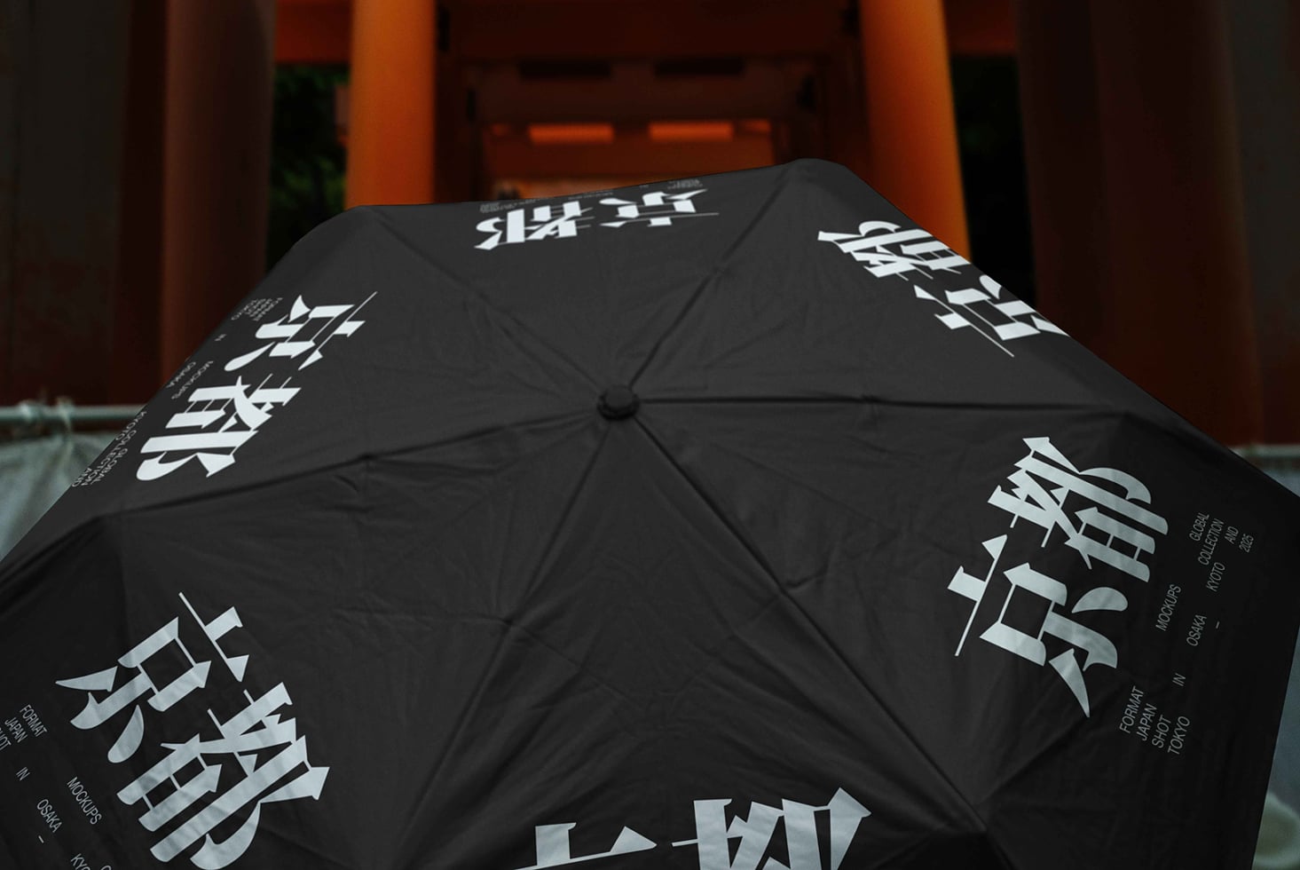 Black umbrella with white Asian characters printed across panels, opened in front of orange architecture