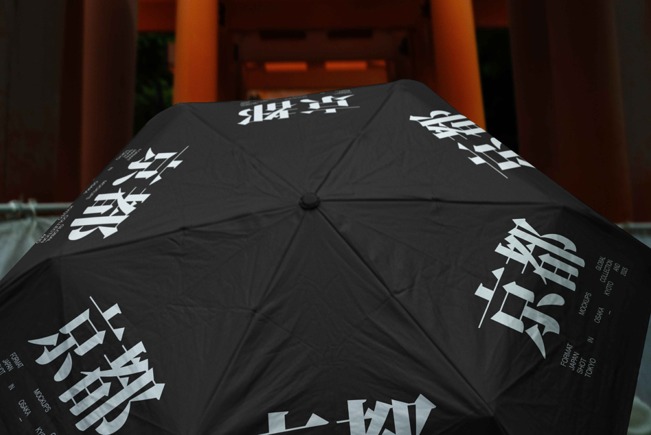 Black umbrella with white Asian characters printed across panels, opened in front of orange architecture