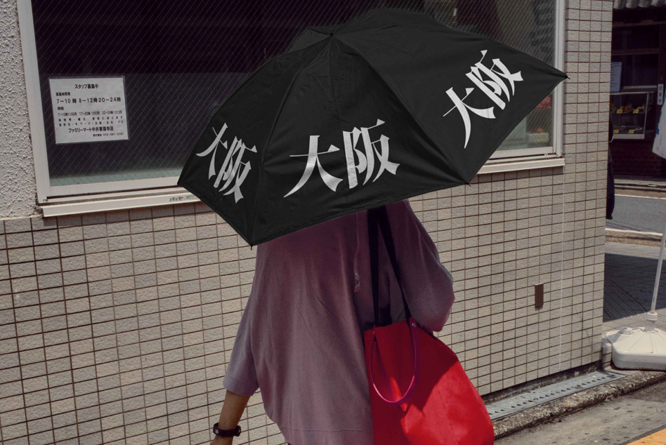 Black umbrella with large white kanji characters held on rainy street in Japan