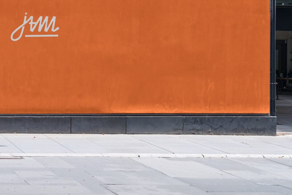 Bright orange storefront wall with Jam logo in corner, clean minimal signage display