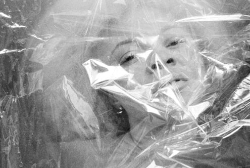 Black and white close-up faces wrapped in clear plastic film texture